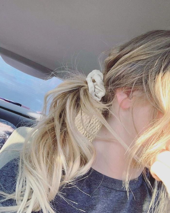Woman styling her hair with a scrunchie in a casual 90s inspired look
