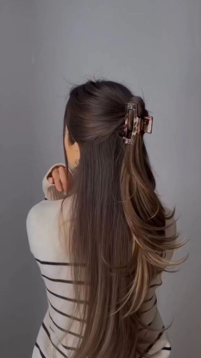 Woman styling her thick hair with a quick claw clip for a casual look
