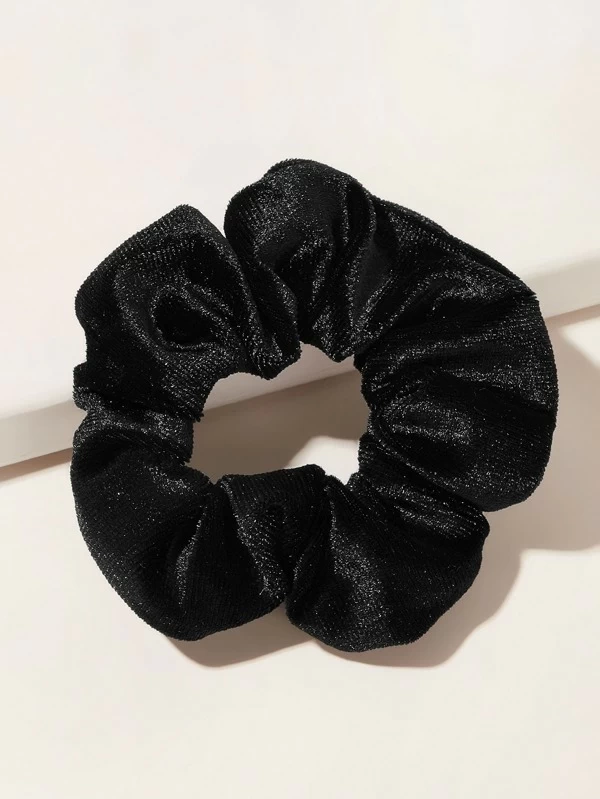 A woman with a simple velvet scrunchie holding a loose updo, perfect for a cozy winter casual look