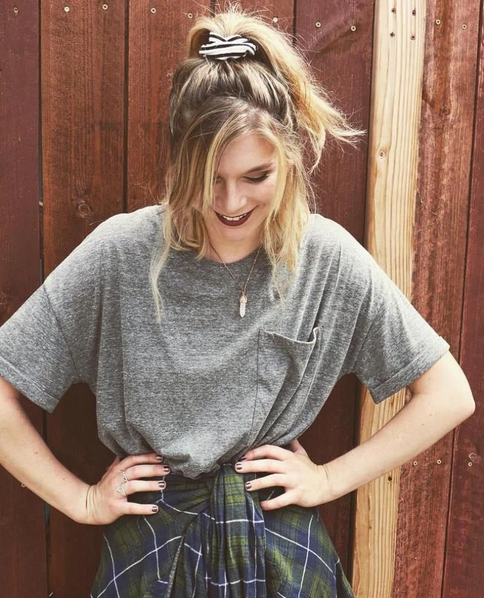 Young woman styling her hair with a scrunchie for a 90s casual look