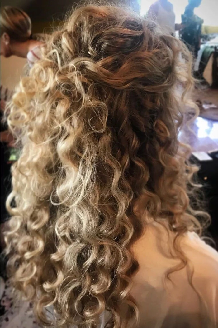 Curly half upstyle adorned with delicate floral pins for anniversary date