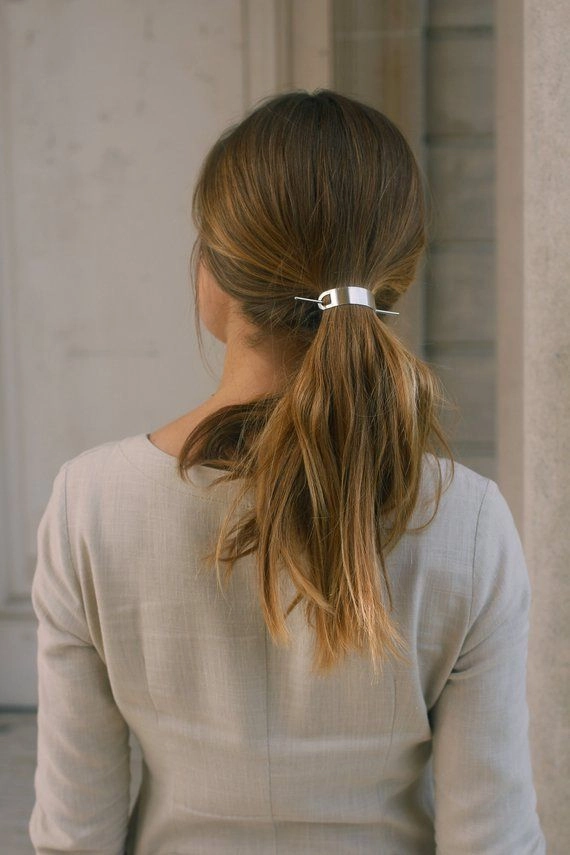 Woman wearing a sleek ponytail decorated with shiny metallic hair cuffs for a date night look