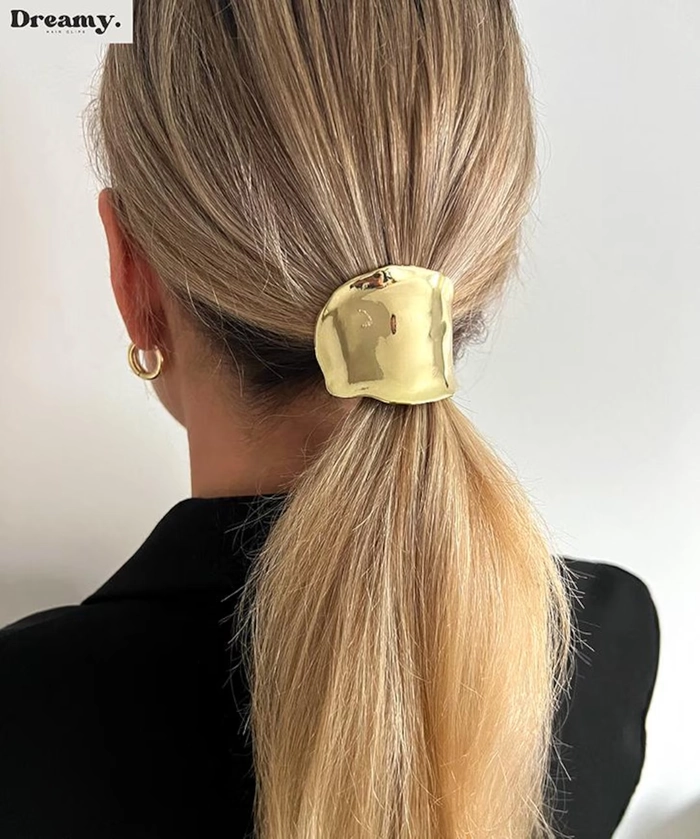 Woman wearing a sleek ponytail with shiny metallic hair cuffs for a date night look