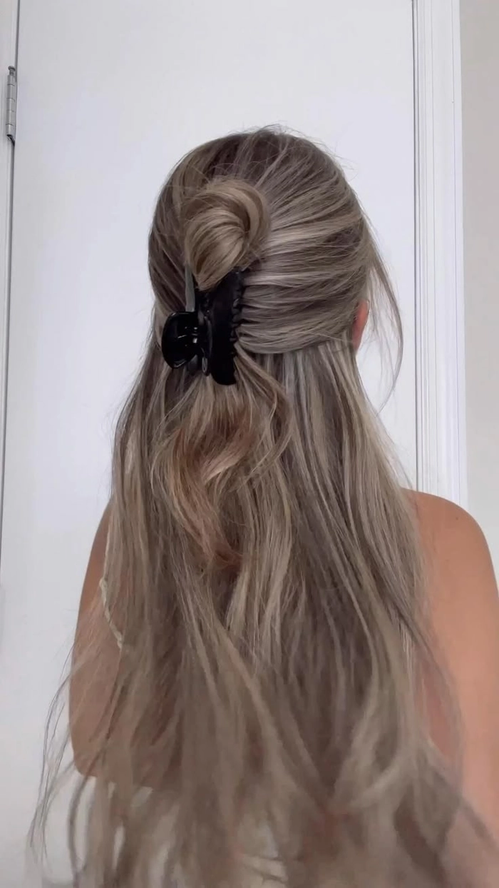 A romantic half up hairstyle secured with a claw clip for a date night look