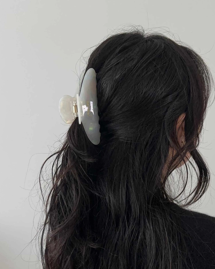 A half up hairstyle secured with a decorative claw clip for a romantic evening look