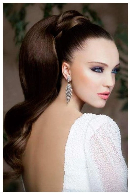 A woman with a long sleek ponytail smiling at a candlelit dinner table
