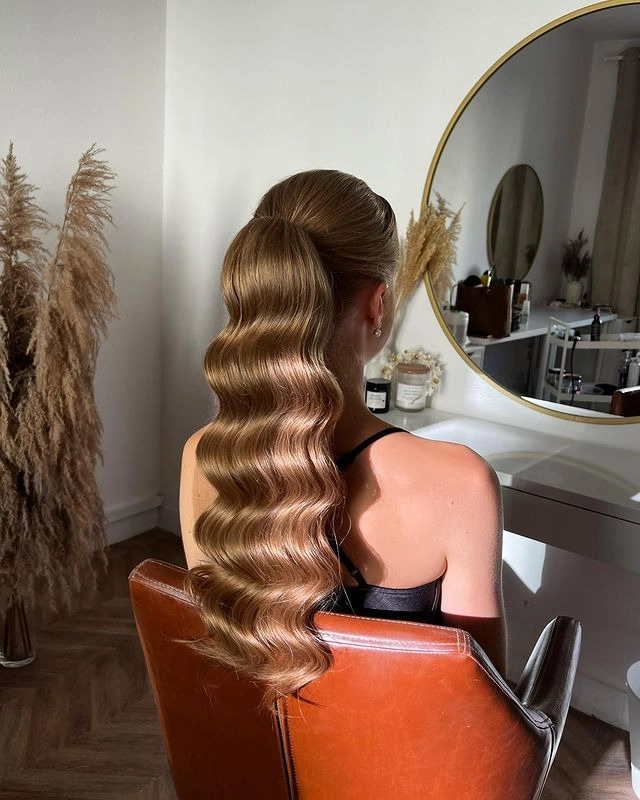 Woman quickly styling her hair at her work desk after hours, transforming a simple office ponytail into a romantic, tousled updo for an evening date