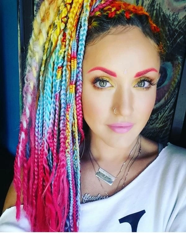 Burning Man hairstyles image 5: Creative festival look with space buns and glowing accessories Burning Man hairstyles featuring a braided updo with desert accessories and colored hair extensions