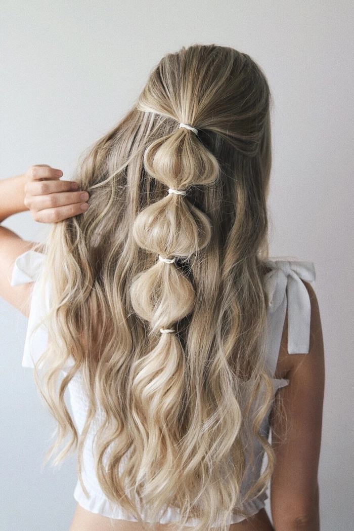 Easy festival hairstyle: side-swept braid with fresh flowers for a boho look A woman smiling with an easy festival hairstyle featuring a side-swept braid and delicate flowers