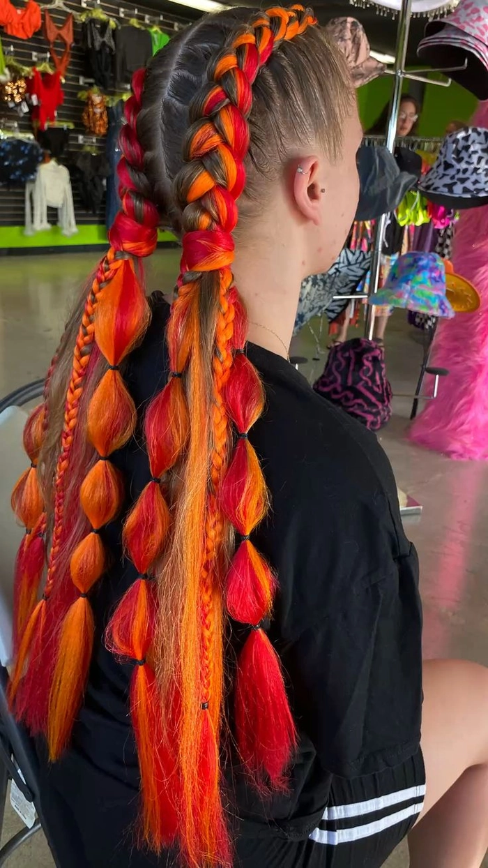 Woman with a flower-adorned Dutch braid hairstyle at a music festival