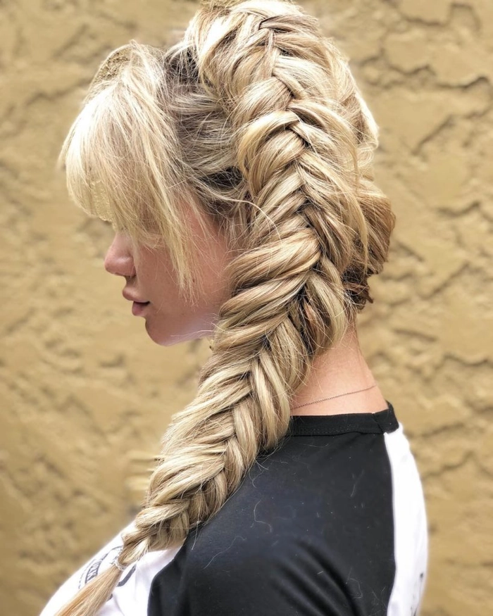 A woman with festival fishtail braid hairstyles adorned with colorful ribbons and beads at a music festival