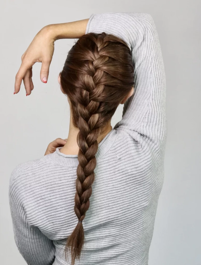 Festival French braid hairstyle with loose waves and tiny flowers woven through the plait