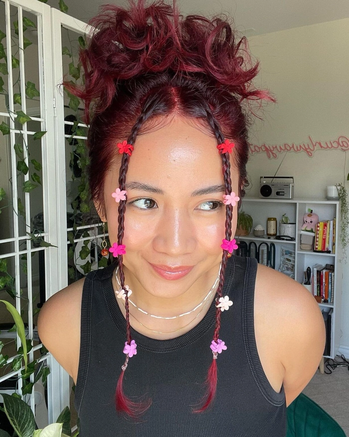 Festival hairstyle for curly hair adorned with tiny braids and floral accents