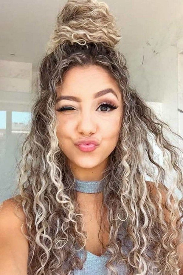Festival hairstyles for curly hair with braided crown and floral accents