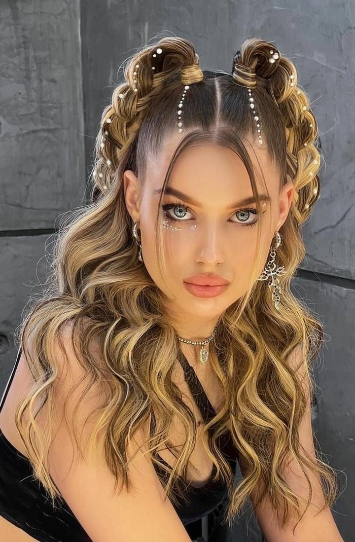 Festival hairstyle inspo for teens with space buns and shimmer accents Teen with half-up space buns and glitter streaks at a music festival