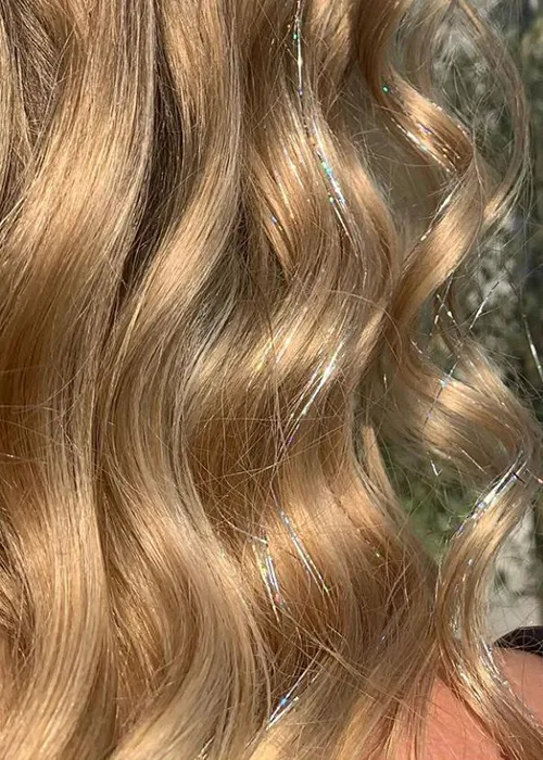Vibrant festival braid with silver and gold hair tinsel woven through, cascading over the shoulder