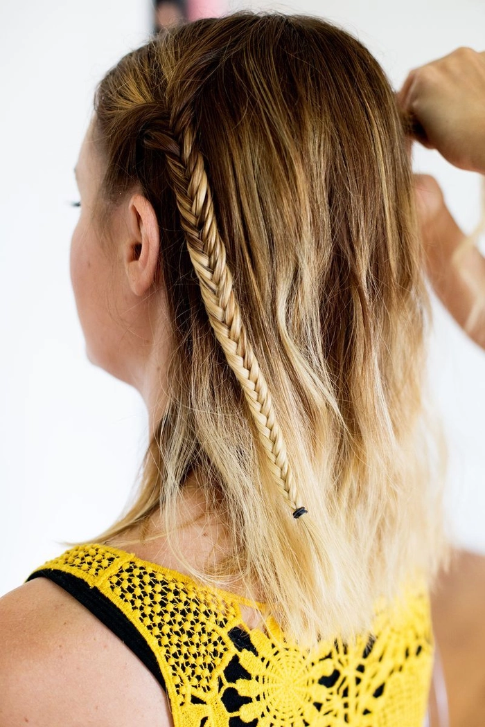 Woman with medium length hair styled in a braided festival updo with floral accessories