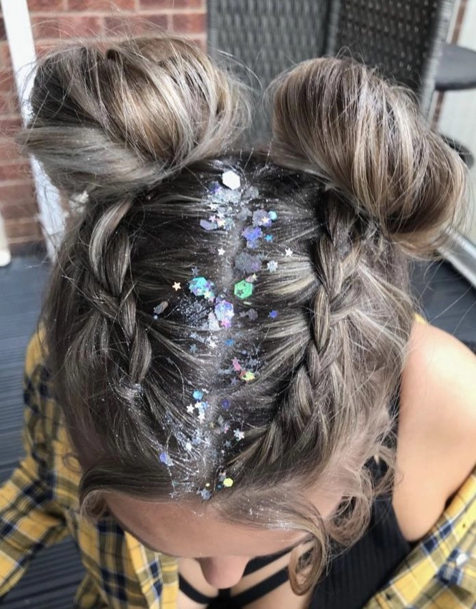 A woman wearing two high space buns decorated with festival ribbons and flowers