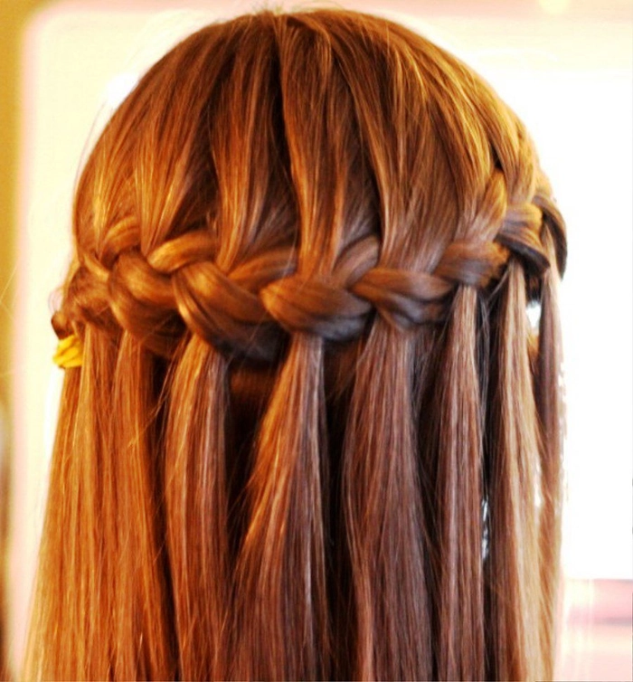Bright festival hairstyle featuring a waterfall braid with delicate accessories A festival waterfall braid adorned with tiny flowers and sparkly pins