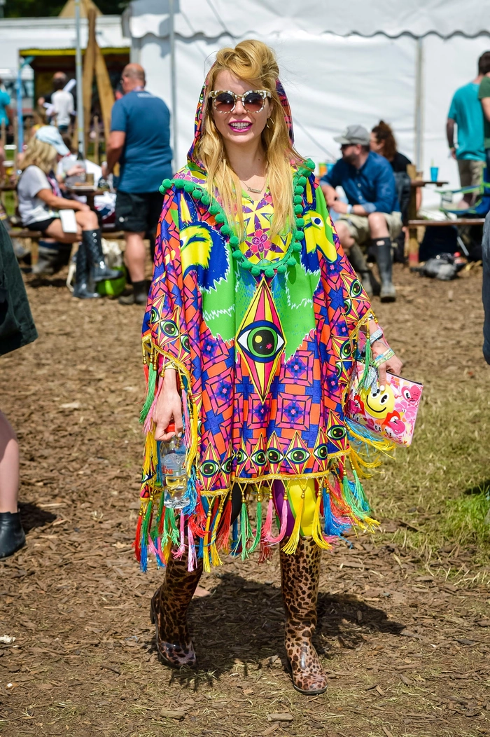 Two braided festival hairstyles with floral accessories against a Glastonbury crowd backdrop