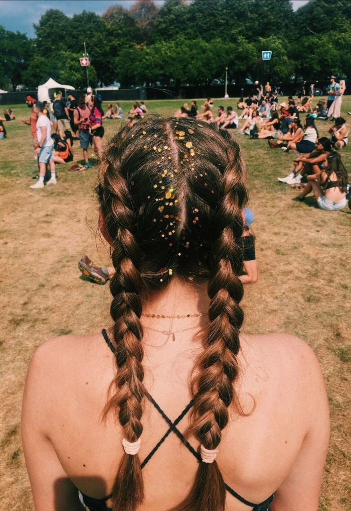 Boho braided Lollapalooza hairstyle with flower accents Festival-goer with colorful braided ponytail and floral accessories at Lollapalooza