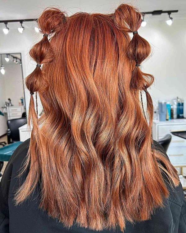 Festival Hairstyles - Third Day Braided Updo with Blooms A model showcasing a third day festival hairstyle with loose waves and floral accents
