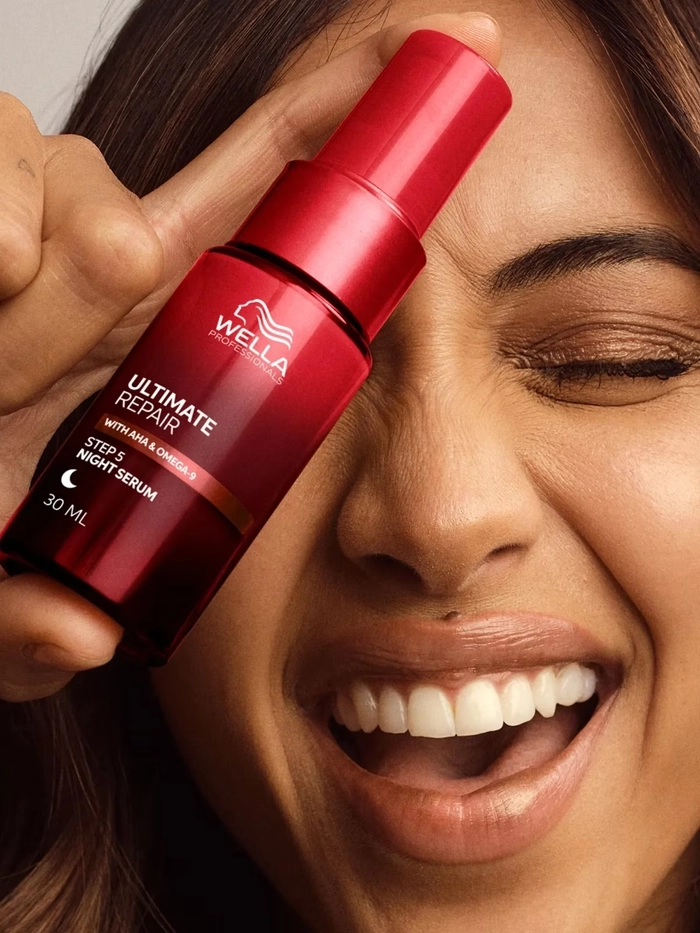A graduate applying anti frizz serum to smooth her graduation hairstyle