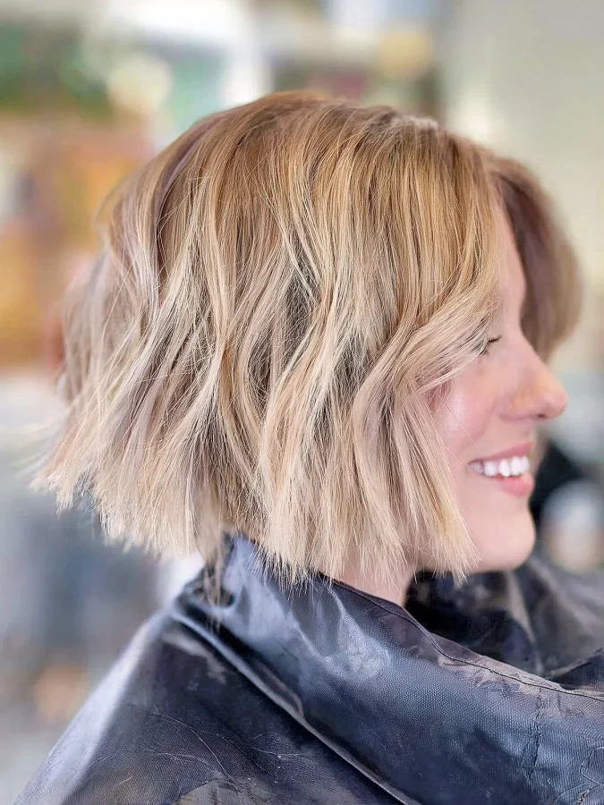 Elegant blunt bob graduation look with subtle texture and shine Graduation hairstyle with a sleek blunt bob cut and soft waves