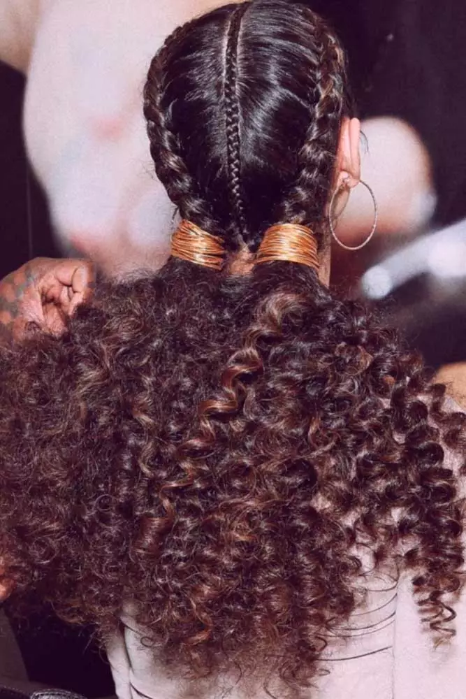 Graduation cap hairstyle with intricate braids peeking out from under the cap