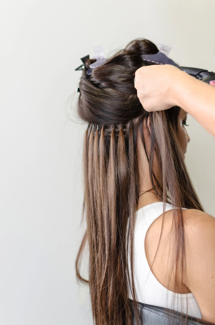 Woman with graduation cap and curly hair extensions blending naturally with her natural hair