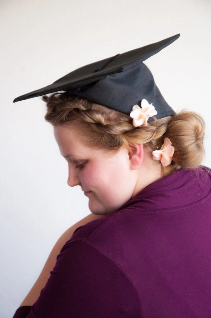 A graduate applying hair products and using a brush as part of a graduation hair preparation routine