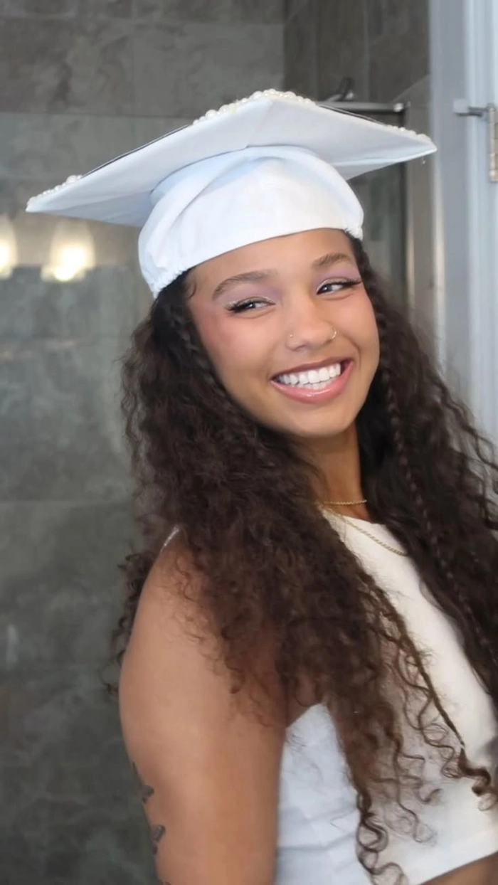 Graduation hairstyle for curly hair featuring a half-up style Curly graduation hairstyle with defined curls and a graduation cap