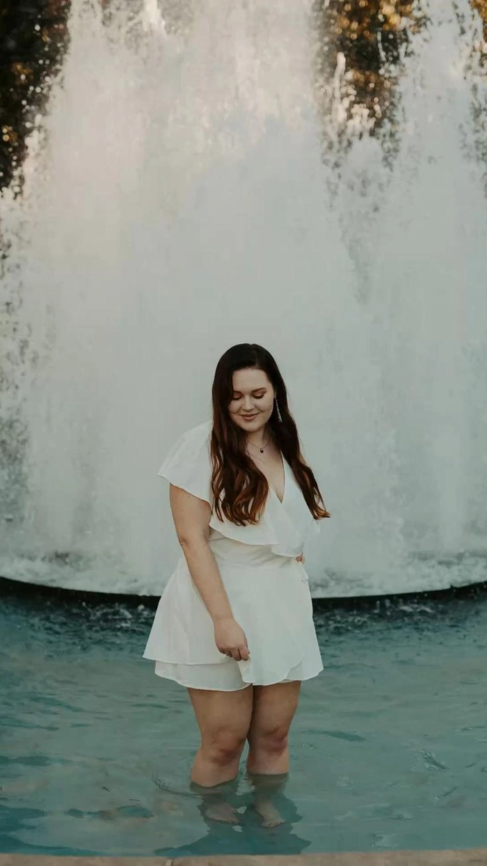 Plus size graduate in a formal gown with a voluminous curly updo hairstyle
