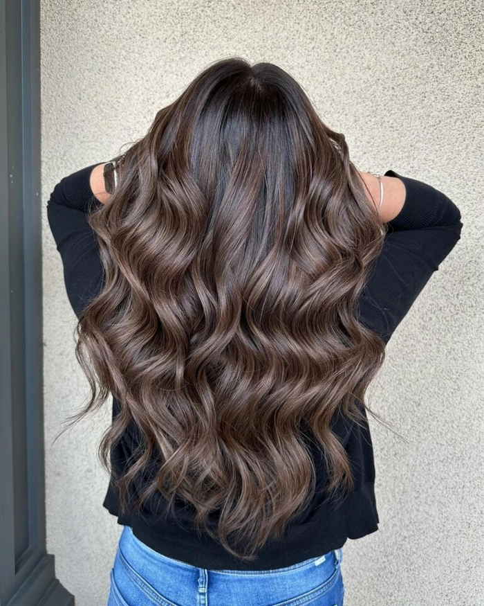 Graduation hairstyle with wavy hair styled in a half-up, half-down look with soft curls and a decorative clip