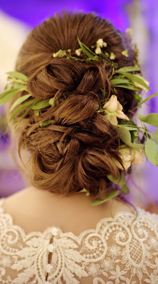 Floral graduation hair design with soft waves Graduation hairstyle with cascading curls and delicate white flowers pinned to the side