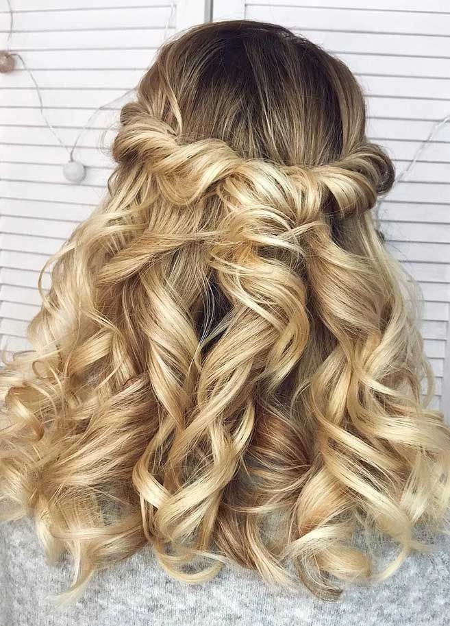 Half up half down graduation hairstyle with soft waves and a pearl clip