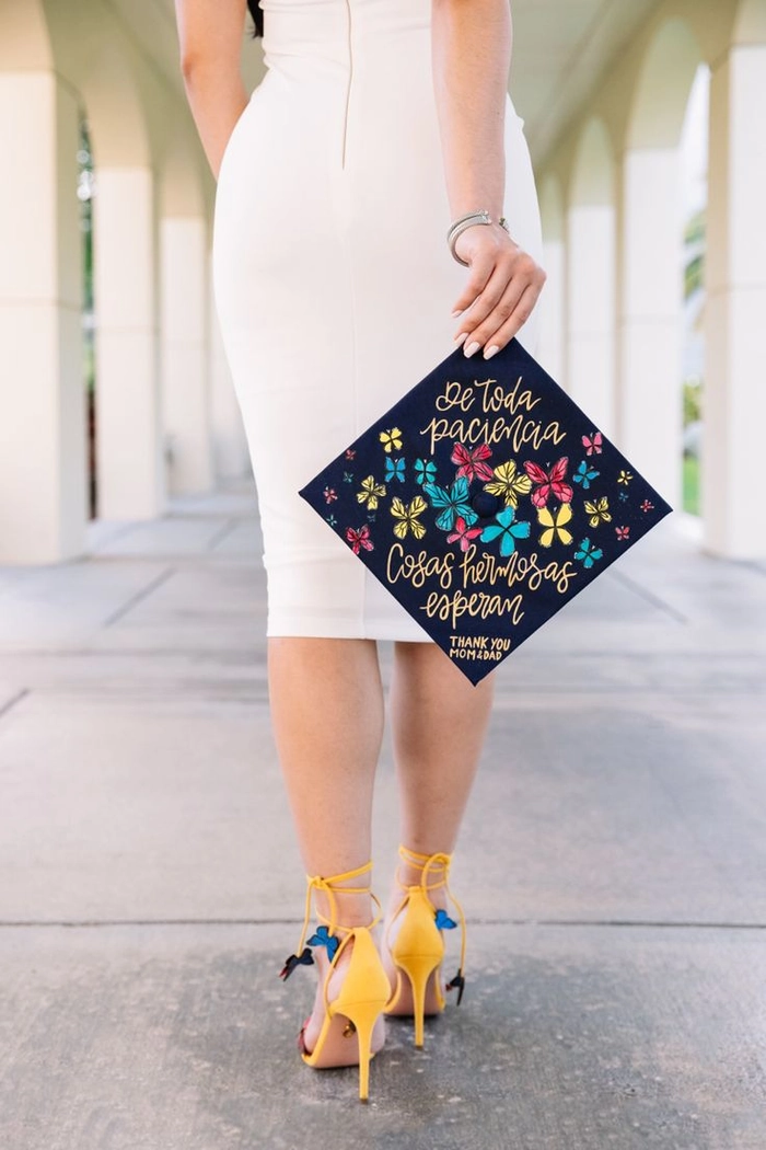 Dry shampoo being sprayed onto hair while holding a graduation cap nearby