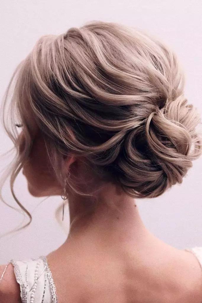 Messy bun graduation hairstyle with soft waves and a cap