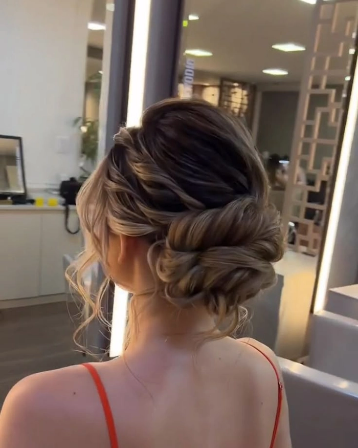 Graduating student wearing a messy bun hairstyle under her cap during an outdoor ceremony