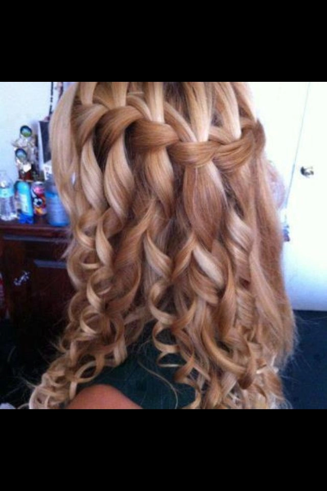 Elegant waterfall braid hairstyle for graduation with soft waves and floral accents
