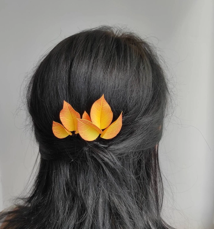 Woman with autumn leaf hair pins in an elegant updo for holiday hairstyle inspiration