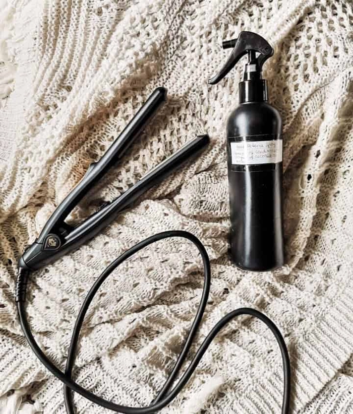 Woman applying heat protectant spray to her curling iron before styling holiday curls