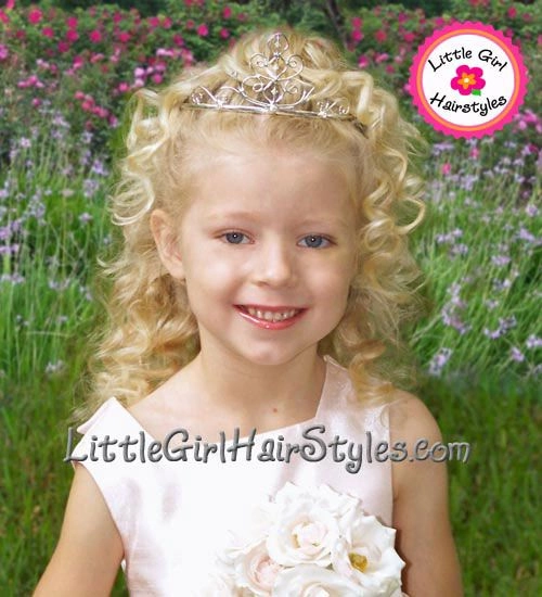 A little girl in a festive holiday dress with a comfortable updo hairstyle, smiling for a pageant