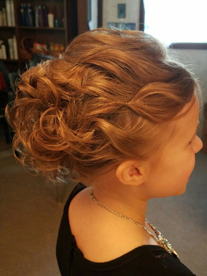 A cheerful child in a holiday pageant wearing a comfortable updo hairstyle with decorative accessories