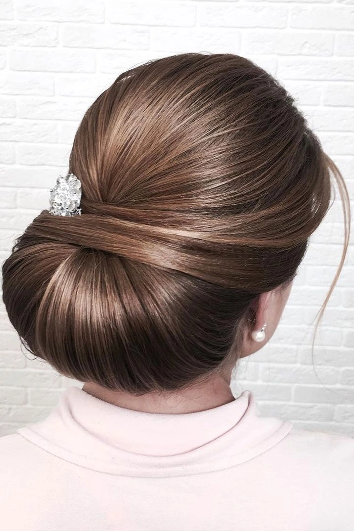Elegant winter wedding chignon with seasonal floral accents and soft waves