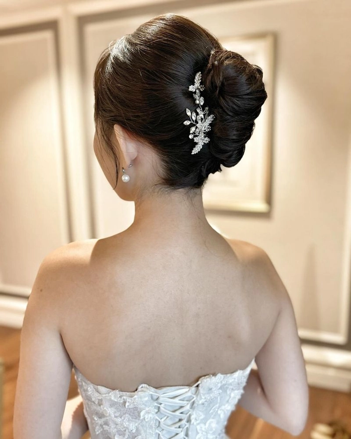 Elegant low chignon with icy pins and white blooms for a winter wedding bride