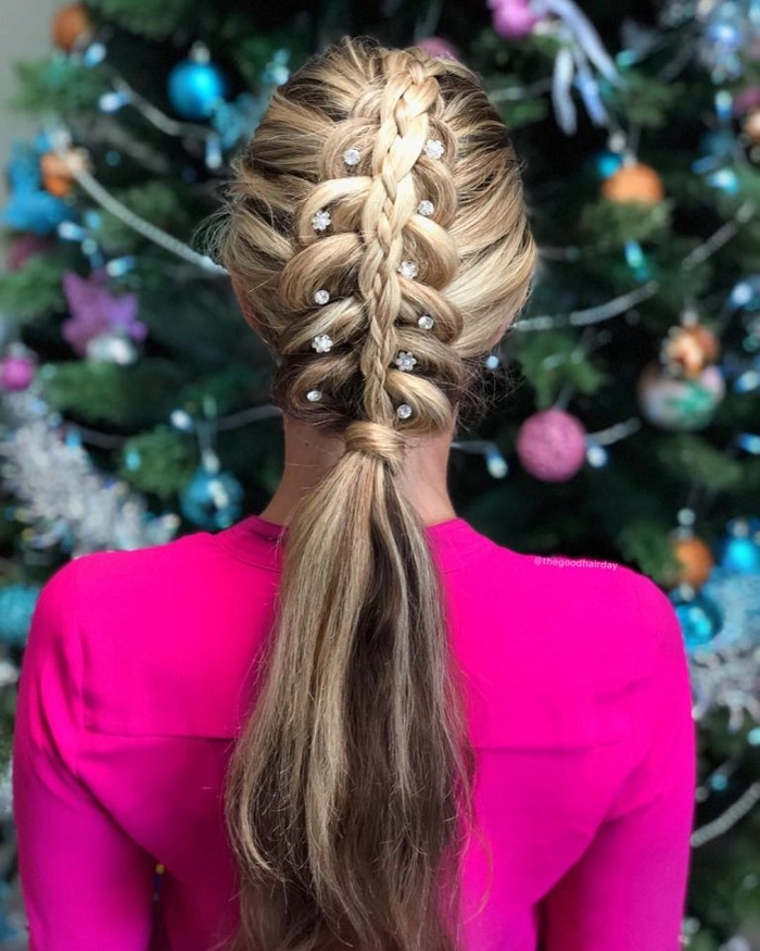 A woman with a festive braided crown hairstyle smiles at a holiday brunch table