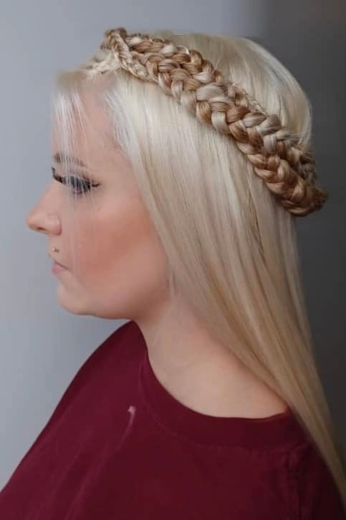 A model wears an elegant braided crown intertwined with sprigs of holly and small gold ornaments for a holiday brunch