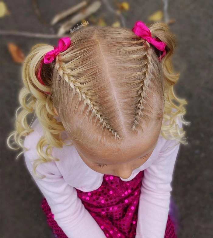 Little girl wearing festive braided pigtails decorated with holiday ribbons