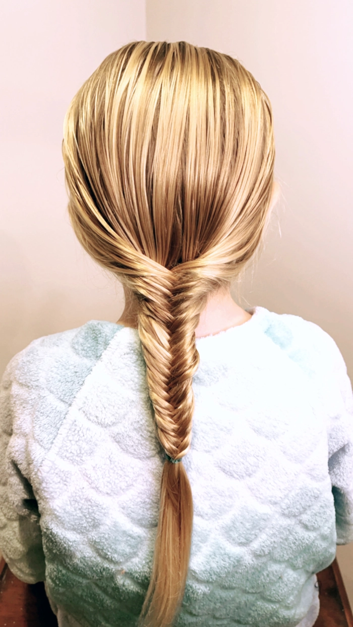 Fishtail braid hairstyle ideas for a casual and relaxed holiday getaway A woman with a loose fishtail braid while enjoying a sunny holiday vacation on the beach